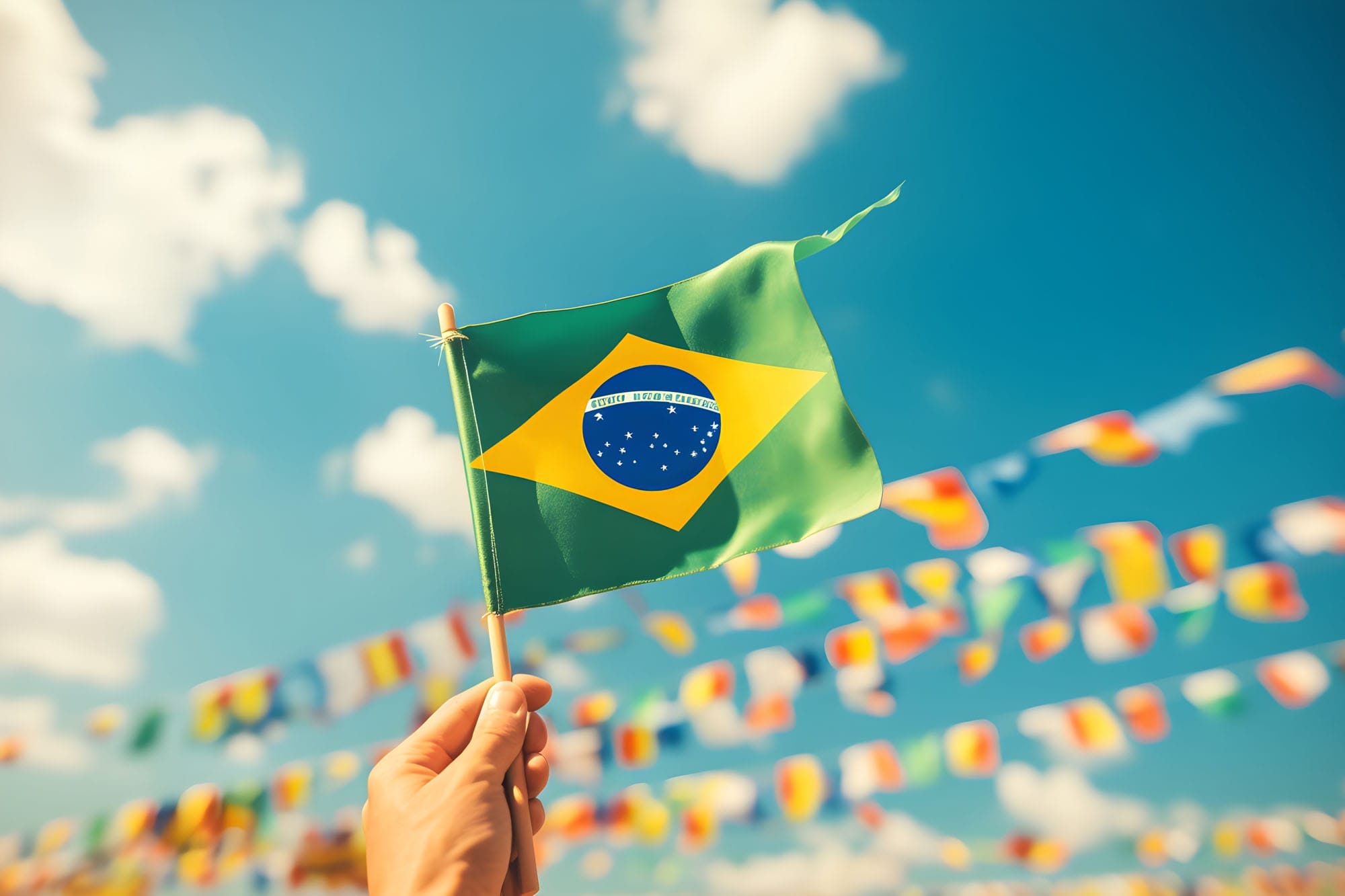 hand holding brazil national flag on blue sky