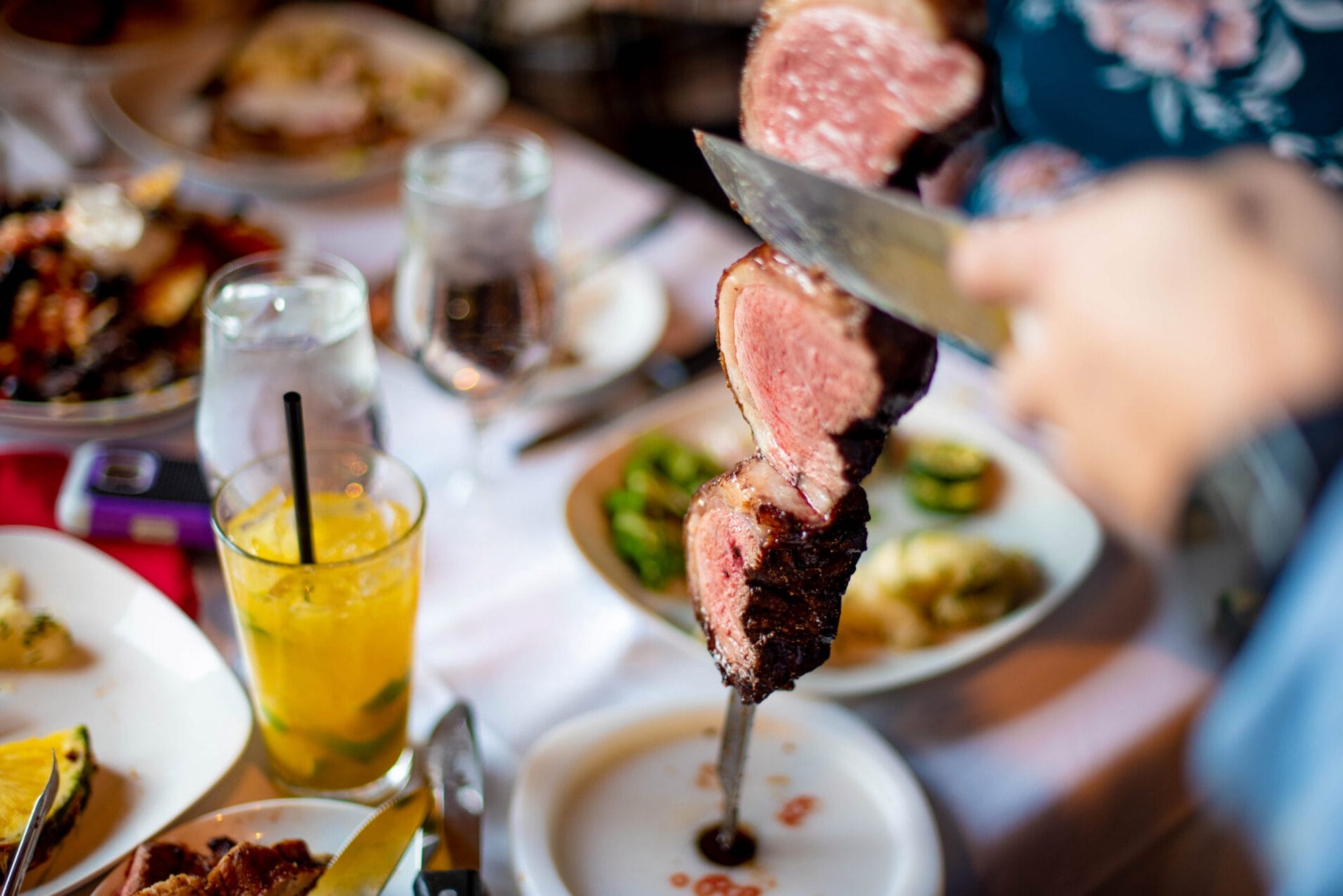 table-of-food cutting meat off a skewer onto a plate